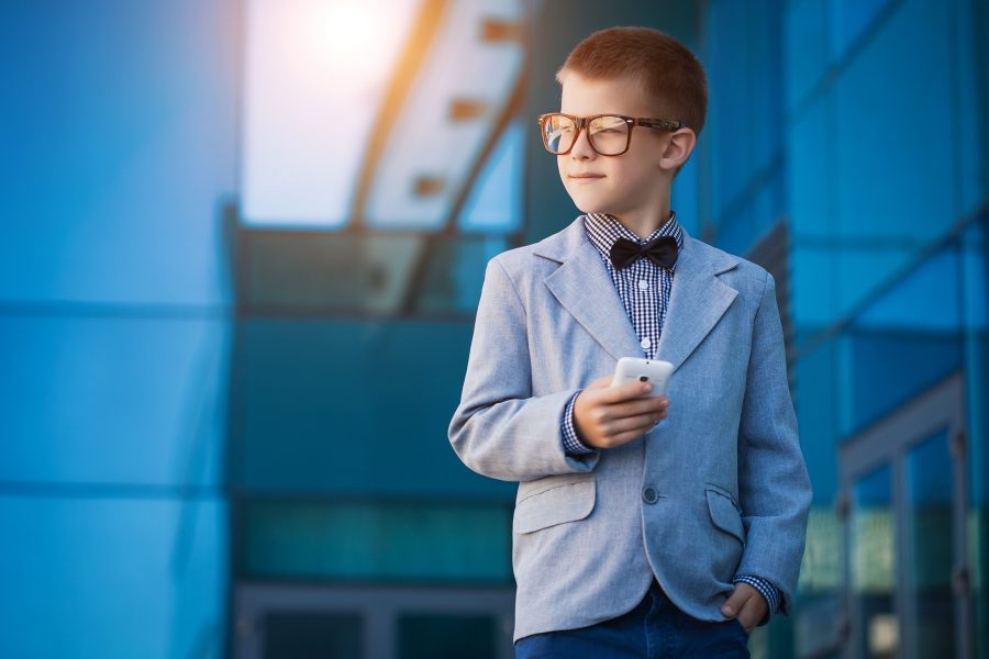 Portrait of a kid businessman next to tall buildings